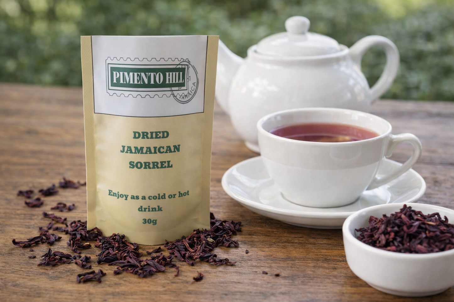Pimento Hill dried Jamaican sorrel tea with teapot and cup, showing deep red herbal infusion and dried sorrel petals on a wooden table.